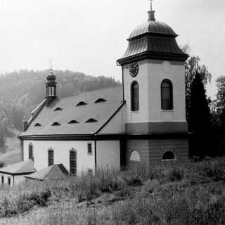 Small rural church with bell tower in hilly landscape.