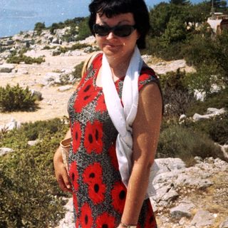 Woman posing by coastal cliffside with ocean view.