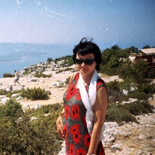 Woman posing by coastal cliffside with ocean view.