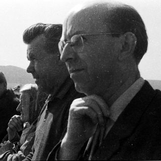 Three men seated outdoors in vintage attire.