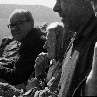 Three men seated outdoors in vintage attire.