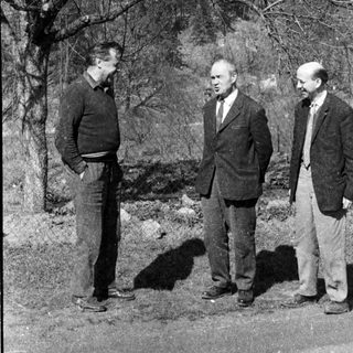 Three men standing outdoors near ruins.