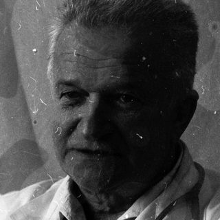 Black-and-white portrait of an elderly man in lab coat.