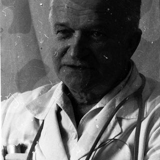 Black-and-white portrait of an elderly man in lab coat.