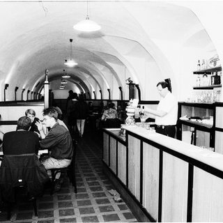 Underground café or bar with patrons seated.