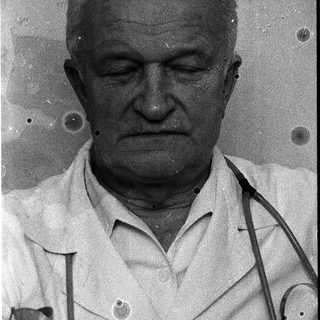 Older man in medical coat with stethoscope.