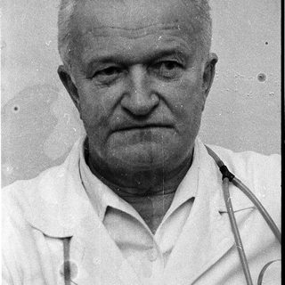 Old man in white lab coat.