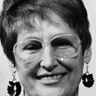 Portrait of smiling woman wearing patterned blouse and large earrings.