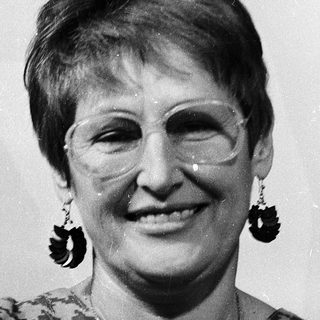 Portrait of smiling woman wearing patterned blouse and large earrings.
