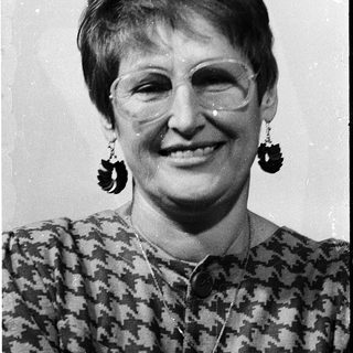 Portrait of smiling woman wearing patterned blouse and large earrings.