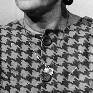 Woman wearing glasses, patterned blouse, and earrings.