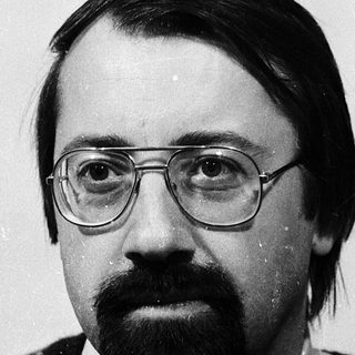 Portrait of a man wearing glasses and patterned sweater.
