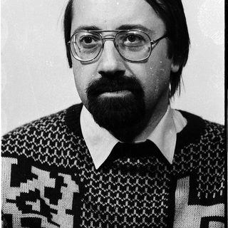 Portrait of a man wearing glasses and patterned sweater.
