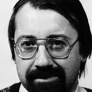 Portrait of a man wearing glasses, sweater, and a beard.