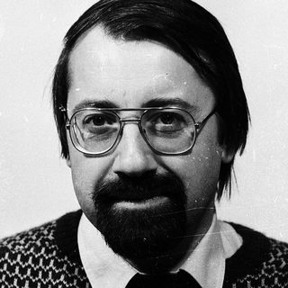 Portrait of a man wearing glasses, sweater, and a beard.