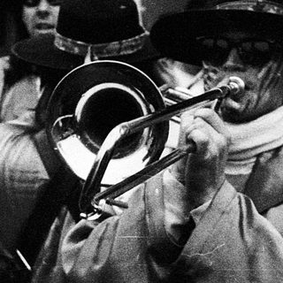 Traditional brass band playing outdoors in historical attire.