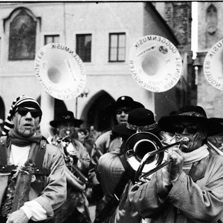 Traditional brass band playing outdoors in historical attire.