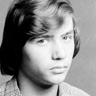 Young man in plaid shirt, serious expression.
