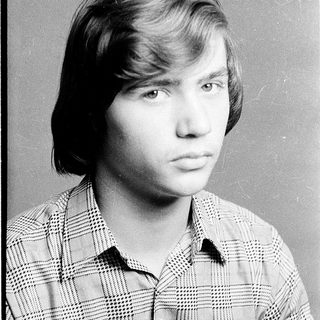 Young man in plaid shirt, serious expression.