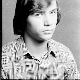 Young man in plaid shirt, serious expression.