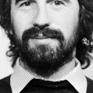 Man with long hair, beard, and mustache in black sweater.