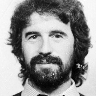 Man with long hair, beard, and mustache in black sweater.