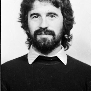 Man with long hair, beard, and mustache in black sweater.