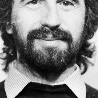 Man with long hair, beard, and mustache in black sweater.