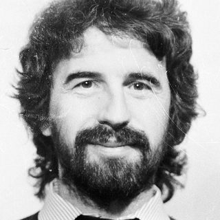 Man with long hair, beard, and mustache in black sweater.