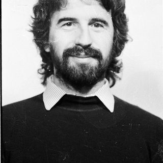Man with long hair, beard, and mustache in black sweater.