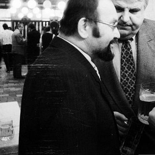 Businessmen conversing at an indoor event.