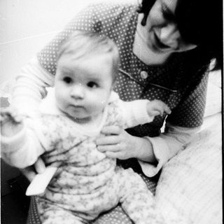 A woman holding and smiling with a baby.