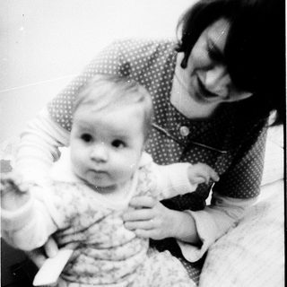 A woman holding and smiling with a baby.