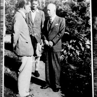 Three men in formal attire outdoors, mid-20th century.