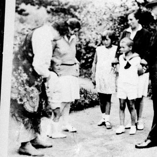 Family group outdoors in vintage clothing, posing together.