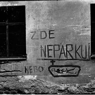 No parking sign on weathered building wall.