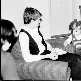 Family moment with man adjusting child's clothing indoors.