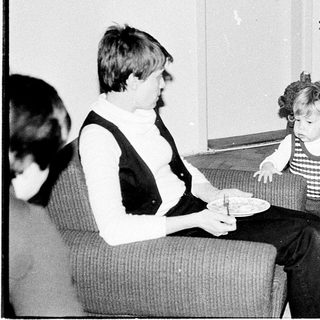 Family moment with man adjusting child's clothing indoors.