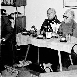 Three elderly women seated indoors during a social gathering.