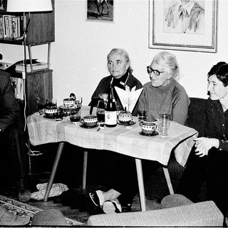 Three elderly women seated indoors during a social gathering.