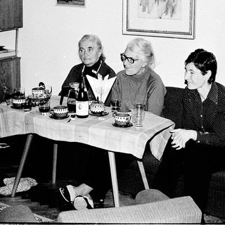 Three elderly women seated indoors during a social gathering.