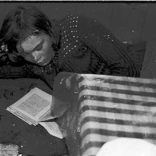 Person reading book while lying on couch.