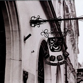 Decorative sign featuring a stylized mask and cross.