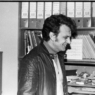 Man smiling in office with filing cabinets.