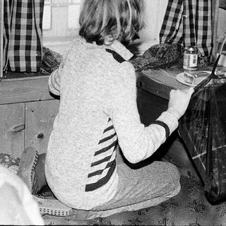 Two women preparing food indoors using vintage kitchen tools.