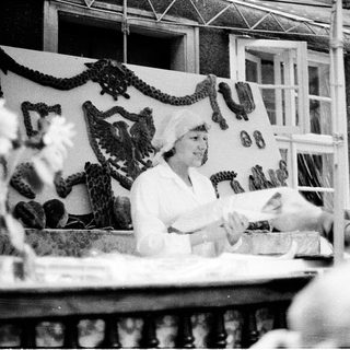 Vintage photo of woman preparing food at outdoor market stall.