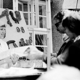 Vintage photo of woman preparing food at outdoor market stall.