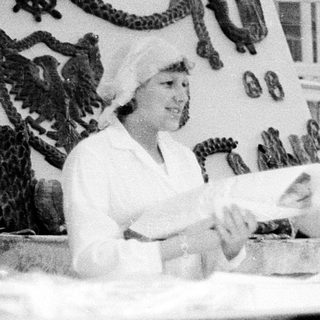 Vintage photo of woman preparing food at outdoor market stall.