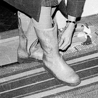 Person tying shoe indoors near doorway.