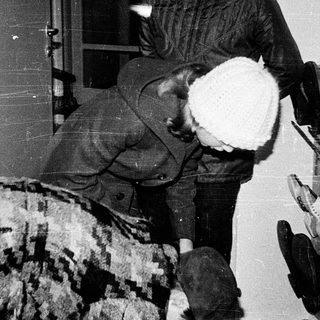 Person carrying large white dog indoors through doorway.
